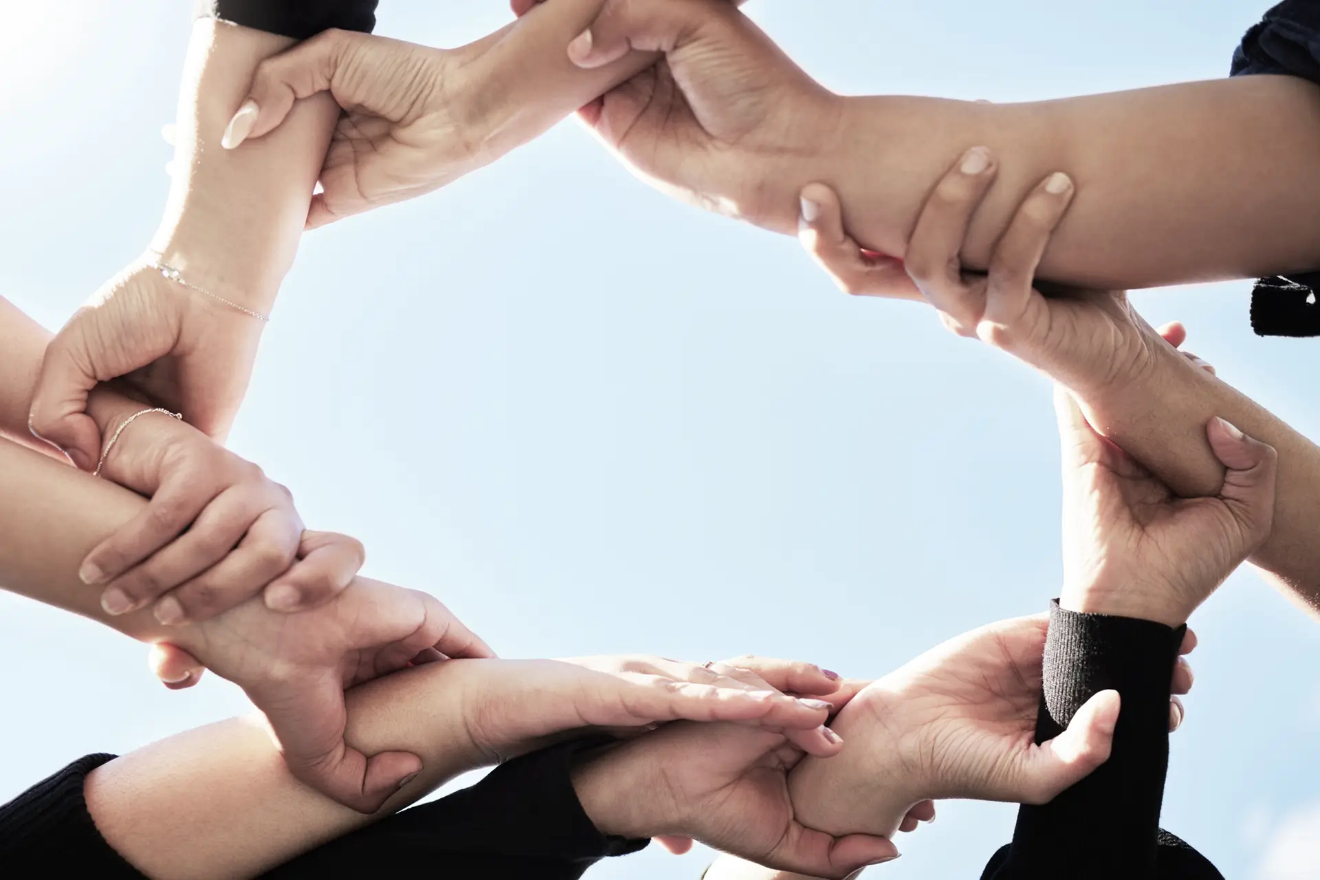 Mehrere Hände greifen ineinander als Symbol für Teamarbeit, Zusammenarbeit und Leadership Workshops