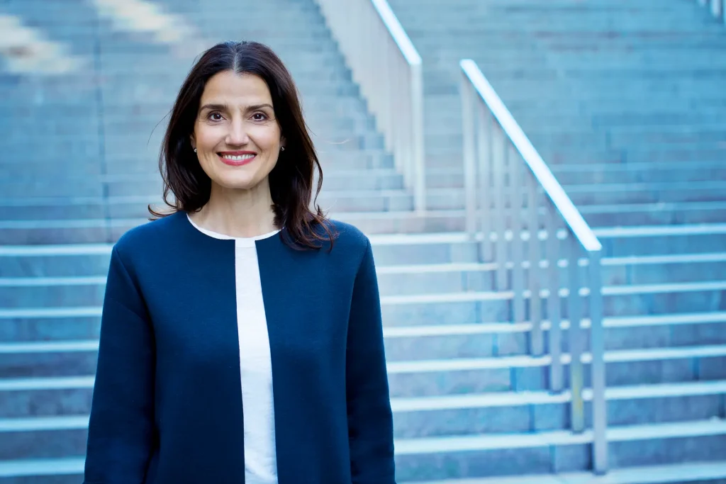Irena Mila Steinmeier, Business Coach für Führungskräfte, lächelnd vor einer Betontreppe
