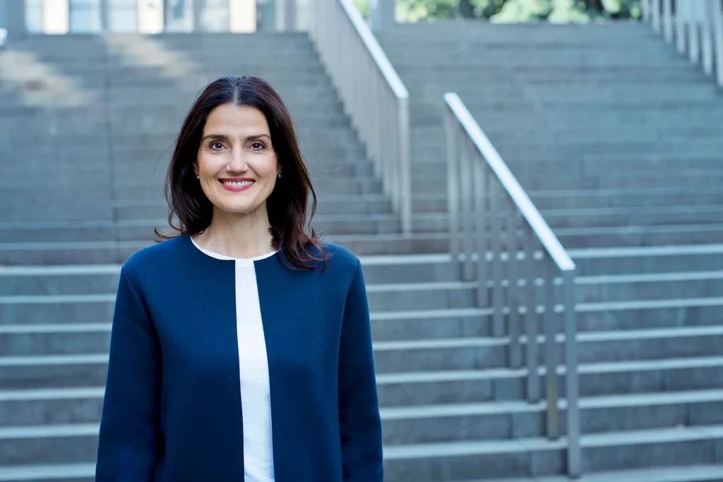 Irena Mila Steinmeier lächelnd vor einer Treppe – Business Coaching für Geschäftspartner