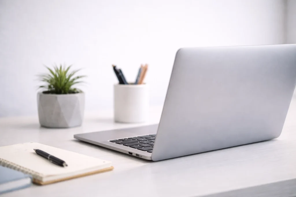 Aufgeräumter Schreibtisch mit Laptop, Notizbuch und Pflanze – Arbeitsplatz für Online Business Coaching