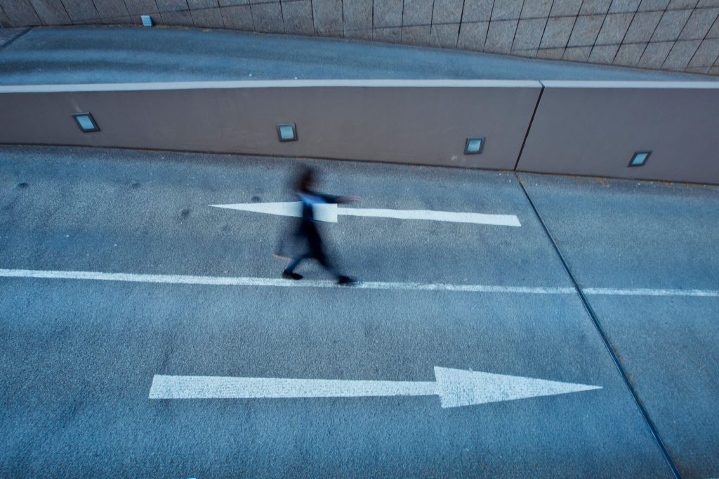 Person geht über einen Asphaltplatz mit aufgemaltem Pfeil – Richtung finden im Online Coaching