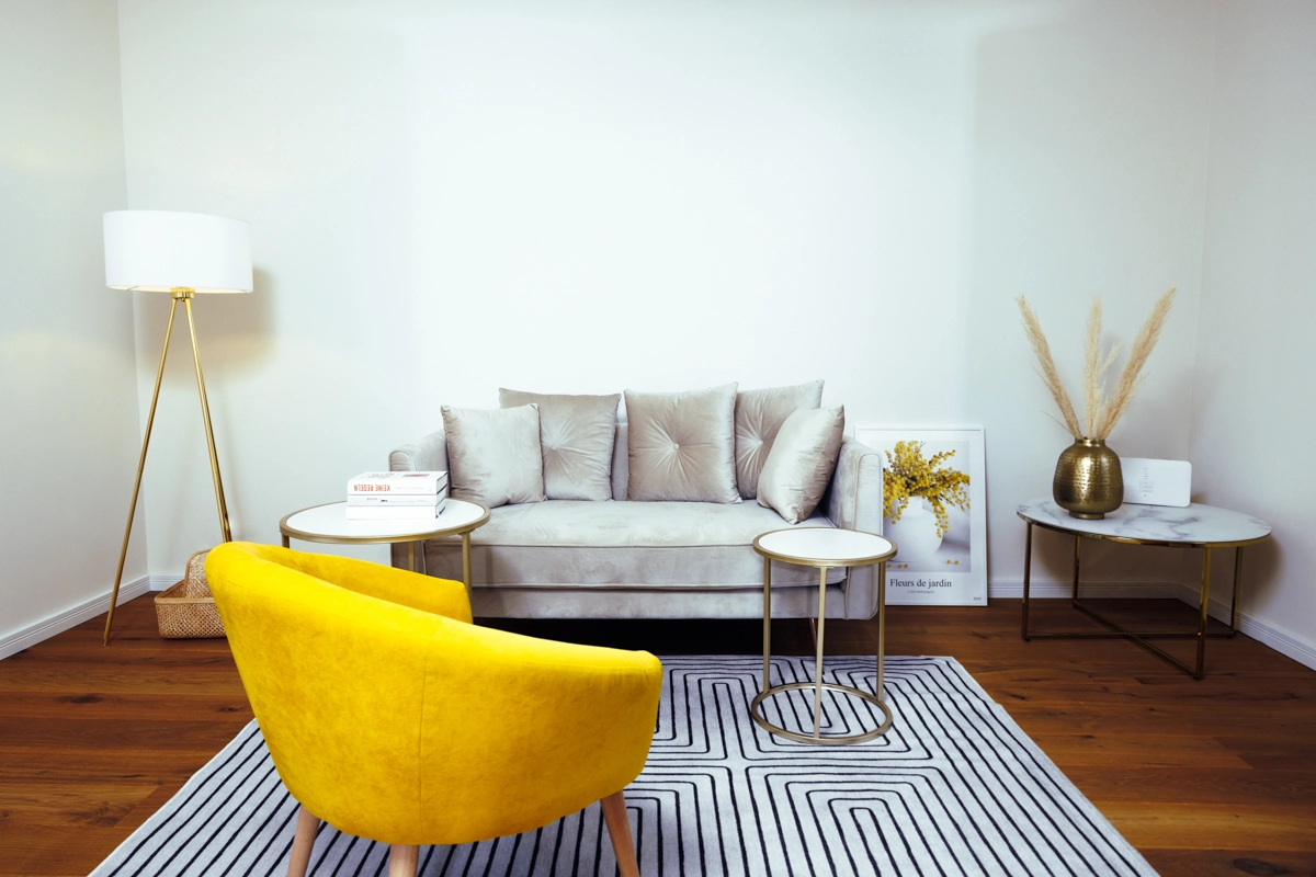 Sitzecke mit hellem Sofa, gelbem Sessel und Stehlampe im Raum für Menschen