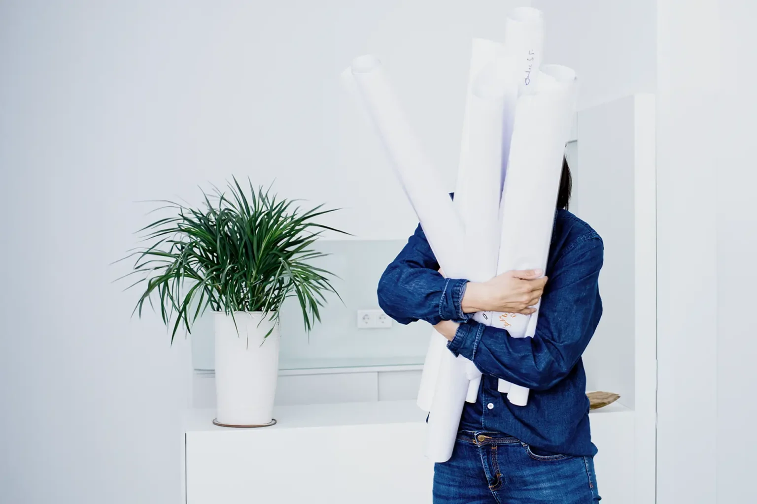 Person versteckt sich hinter großen Papierrollen – Selbstzweifel und Verantwortung im Business